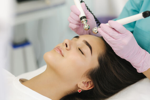 激光柔美女性面部特写皮肤女人在美容诊所做美容手术机器皮肤护理真空