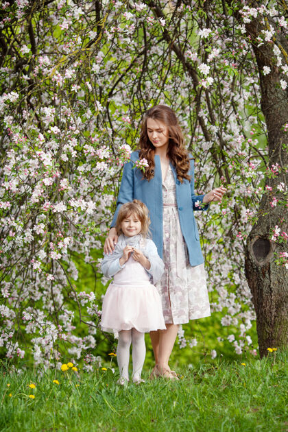 家庭妈妈和小女儿在盛开的苹果里散步花园妈妈我爱她孩子春天故事快乐一家人在美丽的春日里复活节年轻快乐