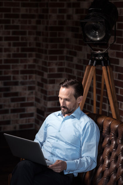 设备参与过程帅哥个体户勤劳的人 膝盖上抱着一台笔记本电脑 一边看屏幕 一边专心工作书房外遇房间