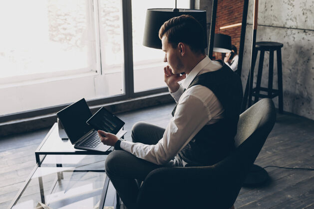 肖像一个成年白种人经理拿着一个平板电脑靠着窗户和他的员工打电话的背面照片成人房间年轻人