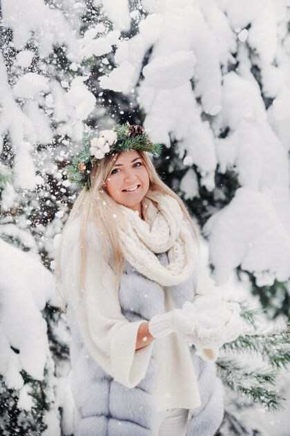 冬天寒冬里穿着白色皮衣的女人的画像森林女孩她头上戴着花圈在冰雪覆盖的冬季森林里冬季森林美丽人