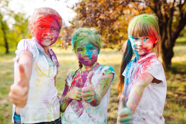 棕榈可爱的欧洲小女孩用五颜六色的颜料粉在脸上和身体上庆祝印度胡里节可爱印度印度
