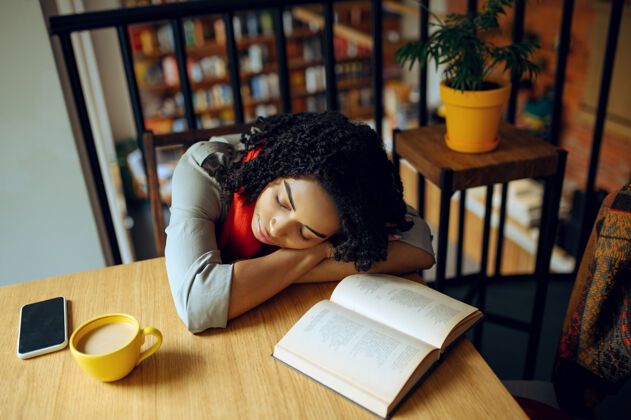 学习疲惫的女学生睡在桌子旁女咖啡馆在咖啡馆学习课程 教育和食物女孩在校园食堂学习女性休息候选人