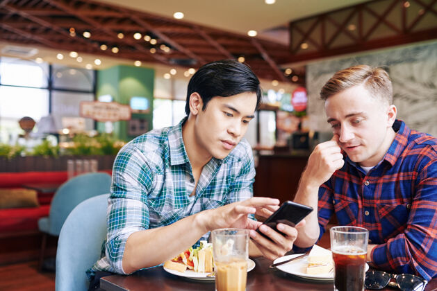 搜索朋友们在咖啡馆吃午餐 通过智能手机上的约会应用程序左右滑动微笑表演桌子