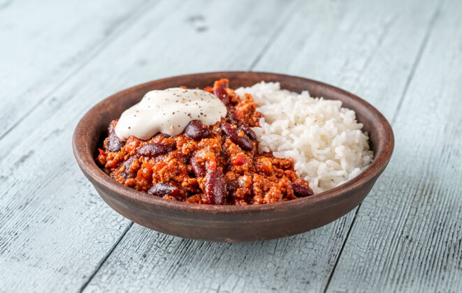 传统一碗米饭和酸奶油的辣椒肉酱香料部分午餐