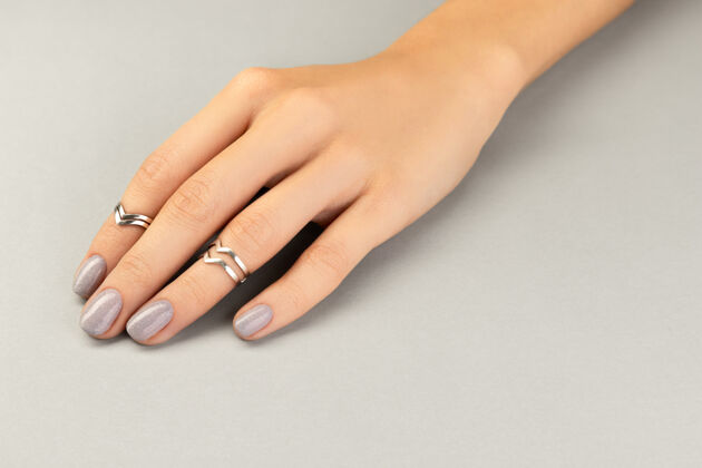 戒指漂亮整洁的女士手与最小的指甲设计在灰色健康治疗女人