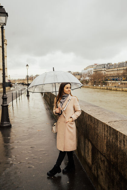 地标时尚的女孩带着透明的雨伞在城市中俯瞰 风景带着模特在雨天年轻云巴黎人