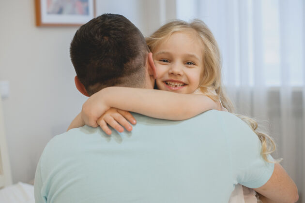 爸爸早上 美丽的小女孩在家里抱着爸爸笑着说室内拥抱惊喜
