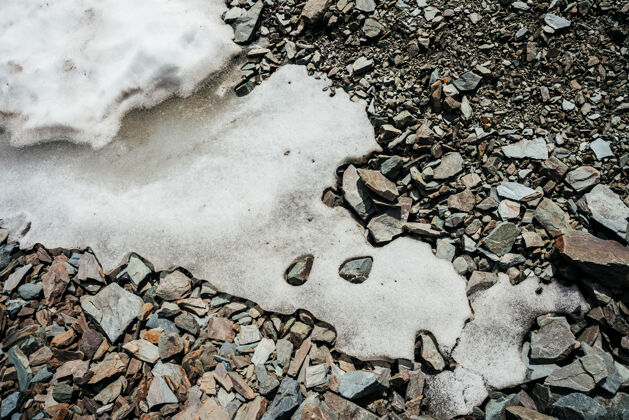 粗糙大自然背景上的雪堆乱七八糟的石头纹理自然全帧