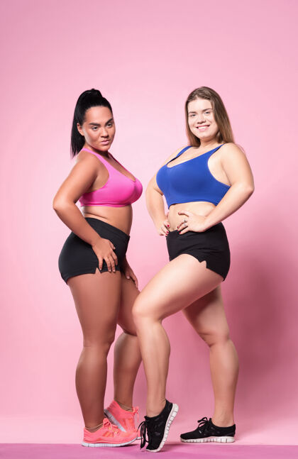 成人胖但是完全适合两位年轻漂亮的超重女士手放在臀部站立的肖像运动装胸罩健康