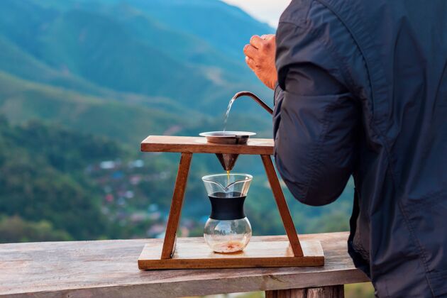 倾倒咖啡师的手把热水从罐子里倒到山顶的阿拉比卡咖啡过滤器里浸泡冲泡人