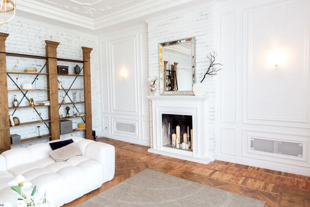 室内设计豪华宽敞明亮的现代室内房间白色昂贵的沙发和木制架子 白色的墙壁和一个豪华的枝形吊灯家庭内部装饰房子