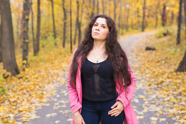 梦穿着蓝色裤子和粉色夹克的女人站在秋天的森林里可爱叶肖像