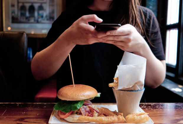 科技一个不认识的女人在手机上给自己的午餐拍照午餐年轻人汉堡