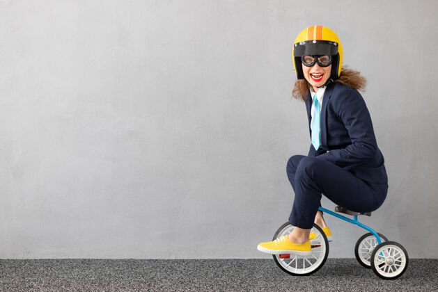 自行车成功的女商人在户外驾驶玩具车城市动机西装