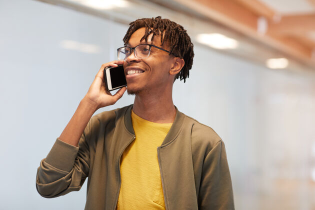 沟通站在办公室边打手机边微笑的非洲年轻人移动现代成功