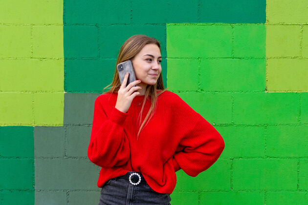 墙壁一个穿着红毛衣的金发少女在用手机说话女性手机年轻人