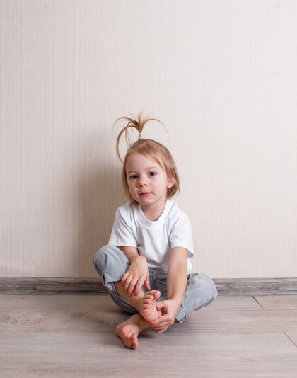 孩子一个穿着白色t恤的小女孩靠墙坐在房间的地板上童年女孩小