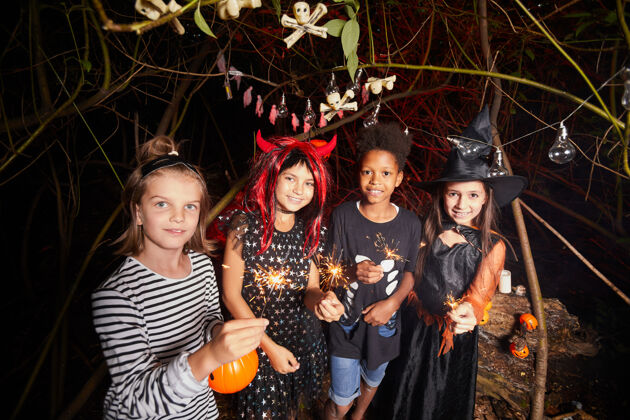 孩子在森林里举行的万圣节派对上 身着盛装的孩子们手持火花 对着镜头微笑的画像幽灵不给糖就捣蛋享受
