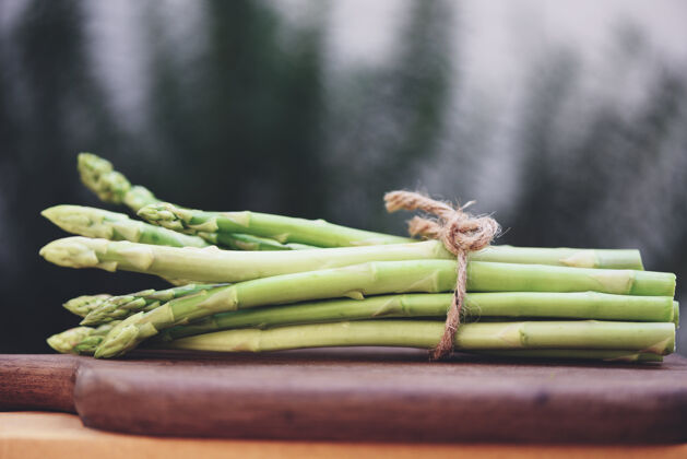 健康一捆芦笋做熟食 一捆新鲜的绿芦笋放在一张质朴的木桌上烹饪配料健康