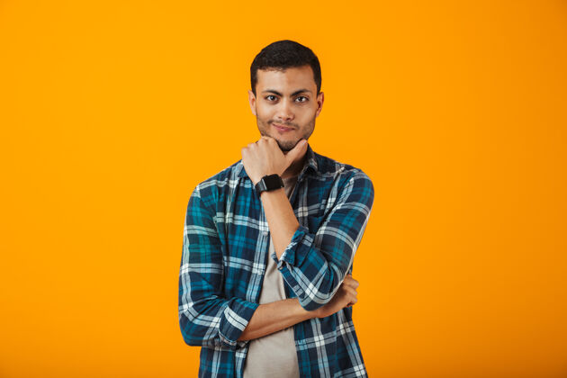 男性一个穿着格子衬衫的沉思的年轻人孤零零地站在橙色的墙上人男人年轻