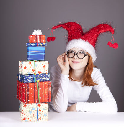 女性滑稽的红发女孩戴着圣诞帽 戴着带礼盒的眼镜圣诞节玩眼镜
