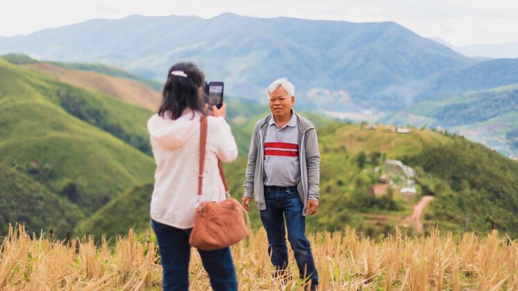 自然亚洲老年夫妇用智能手机在山顶自拍旅游欢乐女人
