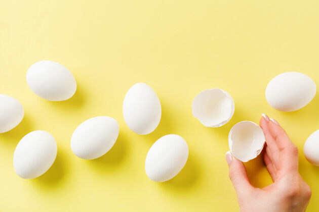 煎蛋卷白色的生鸡蛋躺在黄色的浅色表面上 母手拿着碎鸡蛋食谱工厂半