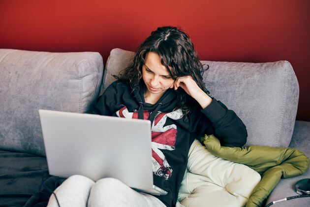房子一个快乐的女人一边在电脑上远程工作一边隔离 一个在家里沙发上的女人个人电脑远程成年人
