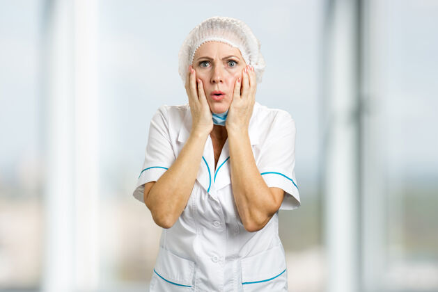 诊所成熟的女医生看起来很震惊惊讶的是成熟的护士手举在脸上 看起来很担心 迷离西装手术肖像