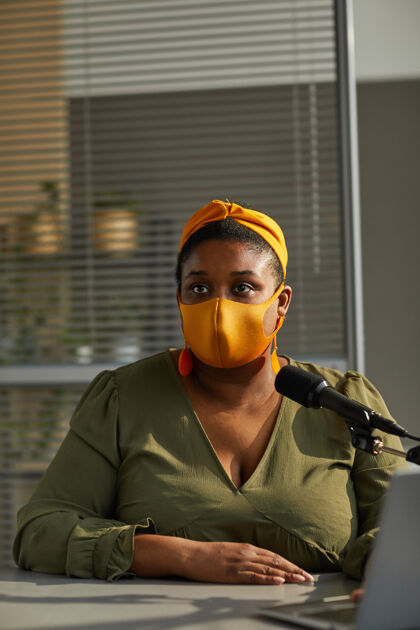 办公桌戴着防护面具的年轻超重妇女在办公室接受采访 她正在大流行期间工作坐着办公室流行病