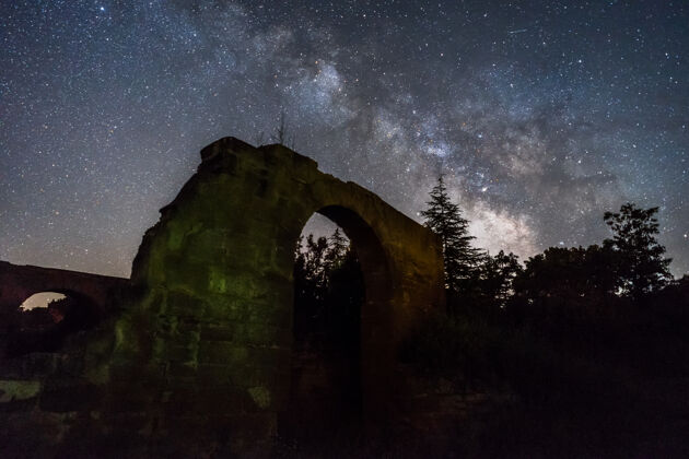 天空夜空与银河以上的森林和废墟在西班牙银河大自然星座