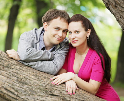 人一对年轻夫妇在树旁的公园里休息放松草地在一起