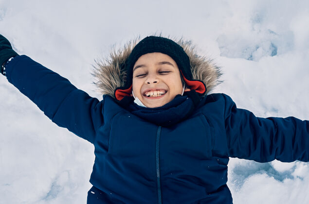 风景一个躺在雪地里微笑的白人男孩天气户外欢乐