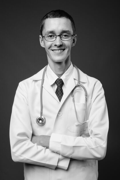 医学年轻人医生戴着眼镜靠着灰色的黑白墙人单色医生
