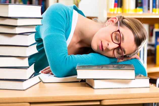 女人学生—年轻女子在图书馆看书学习 她睡着了 又累又累学校学习学生