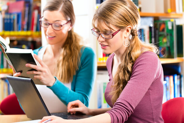 形式学生-年轻女性在图书馆与笔记本电脑和书籍学习小组学习学术人