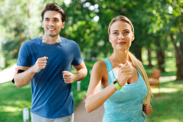 身体有氧运动快乐的夫妇微笑着一起在公园慢跑运动文化快乐情侣