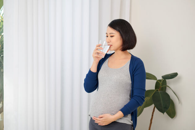 孕妇垂头丧气的孕妇在窗边喝水喝酒期望成人
