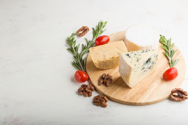 帕尔马干酪蓝色奶酪和各种类型的奶酪 迷迭香和西红柿放在白色木板上板组块