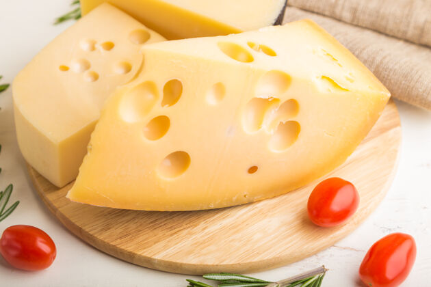 木材各种类型的奶酪与迷迭香和西红柿在木板上的白色木质表面和亚麻织物组意大利桌子