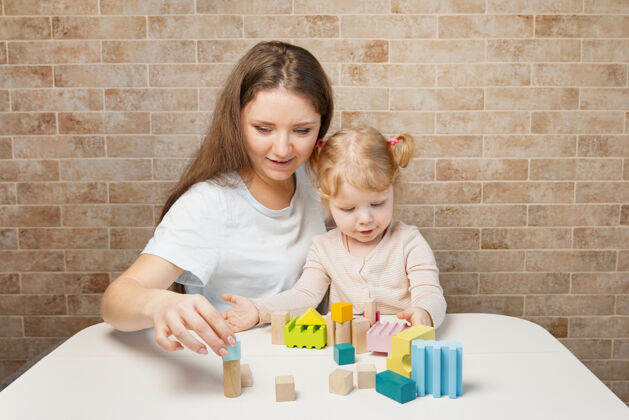 幼儿园母女俩在白桌子上玩积木玩具地板幼儿园拼图