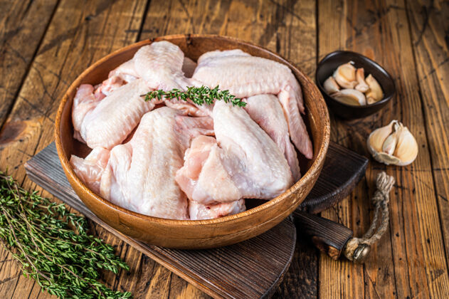 肉鸡把生鸡翅放在一个木盘子里 放上百里香和大蒜家禽烧烤营养