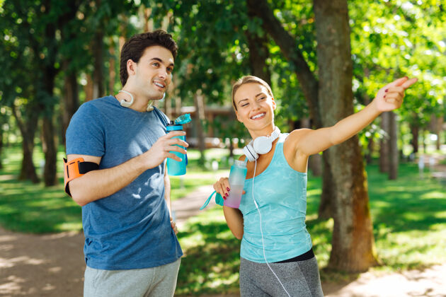 男人水平衡高兴的年轻女子拿着一瓶水和她的男朋友说话朋友形状活跃