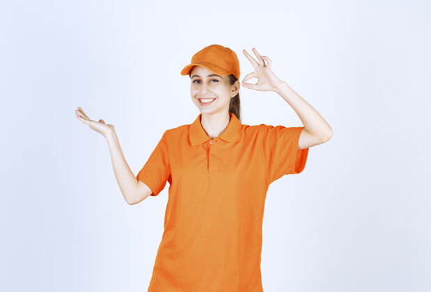 代理女快递员穿着橙色制服 戴着印有“ok”手势的帽子姿势模特送货