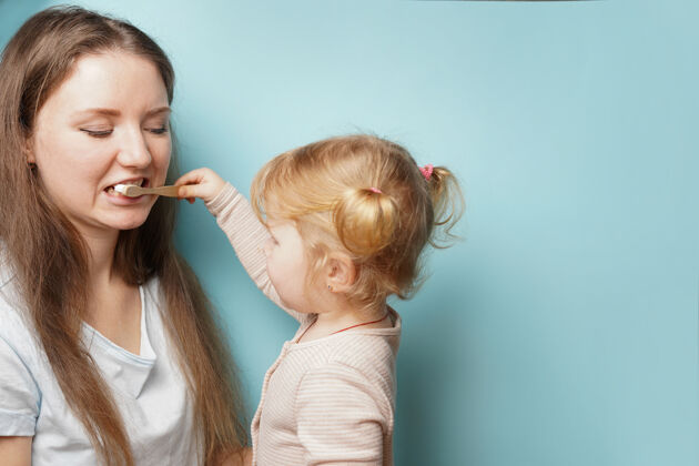 牙科家庭快乐 身体健康母女俩一起在蓝色的表面刷牙童年清洁女人