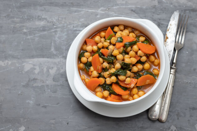 地中海菜鹰嘴豆配胡萝卜和菠菜放在白碗里蔬菜勺子午餐