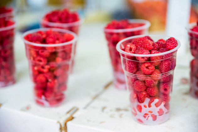 素食者新鲜的覆盆子在市场上出售的塑料眼镜水果多汁甜点