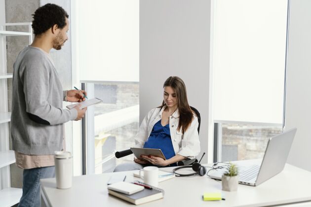 专业人士孕妇和她的同事说话孕妇业务公司