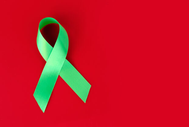丝绸红色表面上的绿色象征丝带病团结治疗